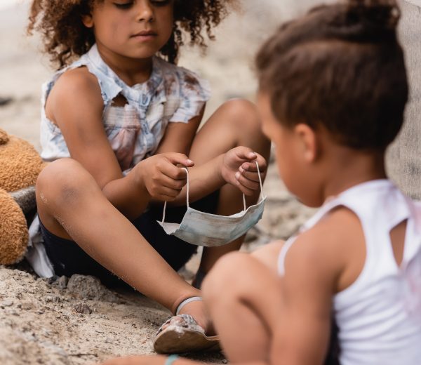 selective-focus-of-curly-african-american-child-holding-dirty-medical-mask-near-poor-brother-sitting.jpg