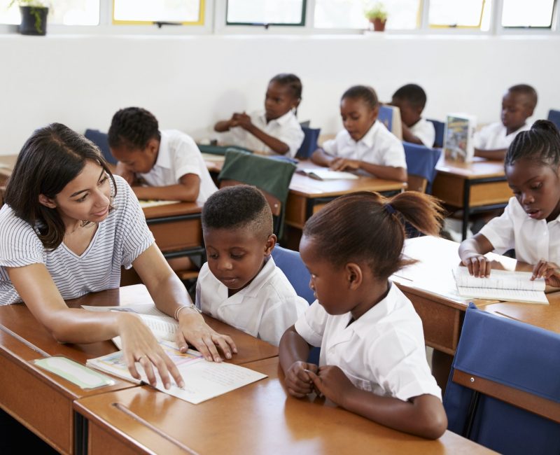 volunteer-teacher-helping-school-kids-at-their-desks.jpg